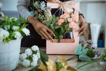 portrait florist preparing a gift flower on table workspace for customer