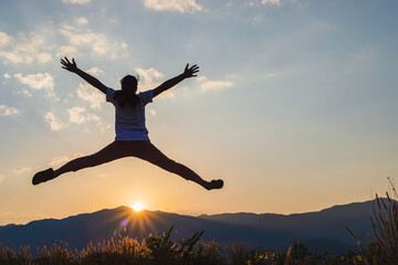 Silhouette of happy child jumping playing on mountain at sunset time