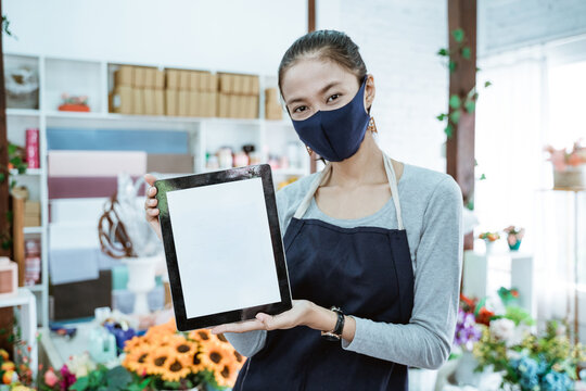 portrait florist woman shopkeeper holding tablet showing qris barcode payment