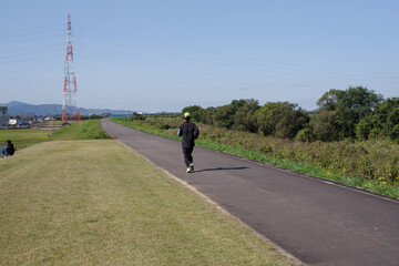 Obraz premium 河川敷の遊歩道を走る男性