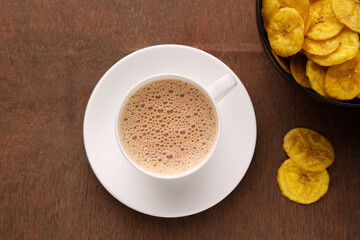 Top view of Indian Chai or traditional beverage milk tea and spices with banana chips Kerala India. Cup of organic ayurvedic or herbal drink India, good in winter for immunity boosting.