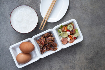 Thai rice gruel eating with side dish crispy squid, boiled egg and spicy sausage salad