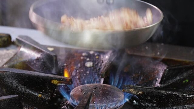 Making fried pork Brasso style - frying the pork meat strips in a pan, tossing and turning them
