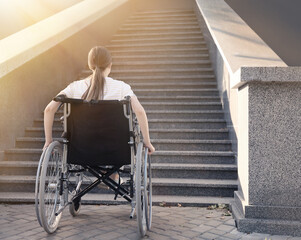 Young woman in wheelchair near stairs