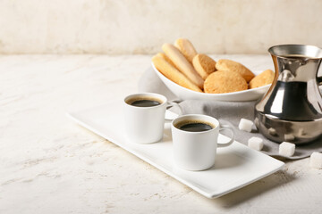Composition with cups of tasty coffee and cookies on light background
