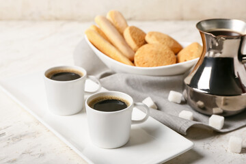 Composition with cups of tasty coffee and cookies on light background
