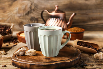 Composition with cups of tasty coffee, beans and sugar on wooden background