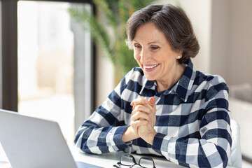 Happy smiling elderly caucasian woman talk on webcam video call on laptop from home
