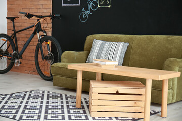 Comfortable sofa with table and bicycle in room