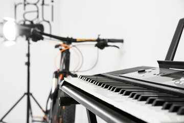 Modern bicycle and synthesizer near white wall in room