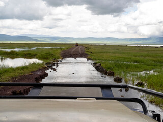 Ngorongoro Crater, Tanzania, Africa - March 1, 2020: Crossing flooded roads in jeep © Elise