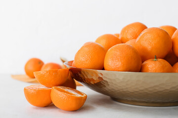 Bowl with sweet tangerines on white background