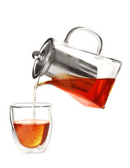 Pouring of hot tea from teapot into glass on white background