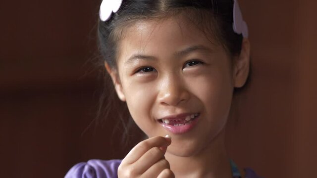Asian Girl Smiling and Holding Lost Tooth &ndash; Child Losing Baby Teeth

