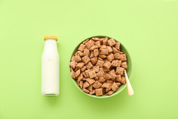 Fototapeta na wymiar Bowl with tasty corn pillows and bottle of milk on color background