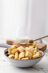Bowl with tasty corn pillows and blueberries on light background