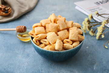 Bowl with tasty corn pillows on color background