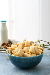 Bowl with tasty corn pillows on color background