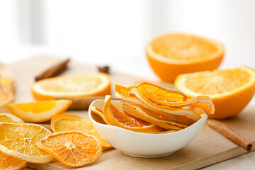 Bowl with dried orange slices on light background