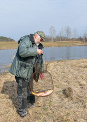 Naklejka premium a fisherman on the shore of a lake, carp caught in the hands of a fisherman, amateur carp fishing, fishing as a hobby