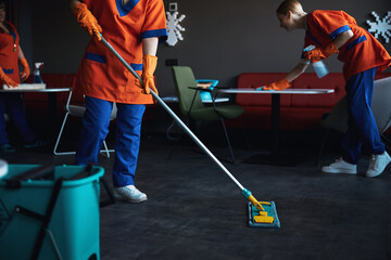 Three female janitors in rubber gloves doing the wet cleaning