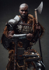 African guy dressed in military nordic costume holding an axe