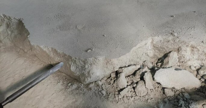 A builder dismantles a perforator drill breaks the concrete floor at a construction site