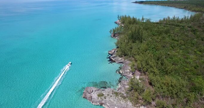 Skiff running full speed alongside an island in the Bahamas.