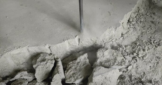 A builder dismantles a perforator drill breaks the concrete floor at a construction site