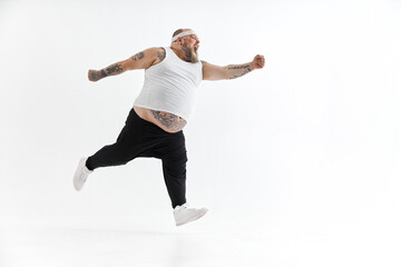 Happy fat man with big belly and tattoes in sports wear posing on white background