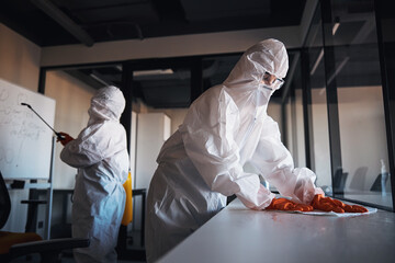 Cleaning staff in protective gear disinfecting the office workplaces - Powered by Adobe