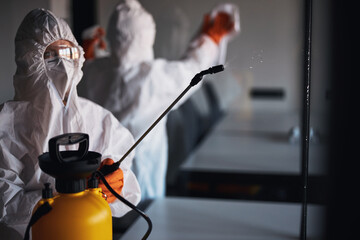 Two people in protective gear cleaning the glass walls