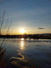 Melting River Ice and Water in Spring Sunset with Mountain on Horizon 