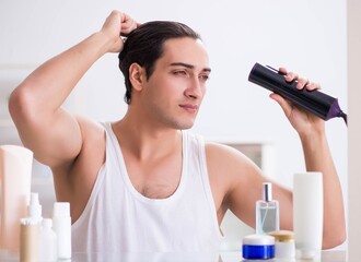 Young man drygin his hair in the morning