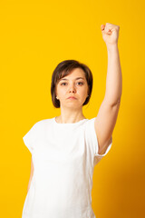 Hooray, its excellent! Serious woman enjoys victory, accomplishes goal successfully, clenches fists, celebrates triumph, isolated over yellow wall.