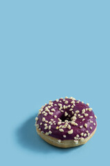 Bright donut with yellow glaze and a multi-colored sprinkle on blue vertical background .Sweet minimalist food image.