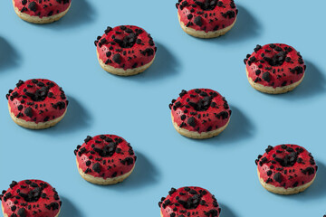 Creative pattern donut design, many red glassed donuts with chocolate biscuit topping on blue background