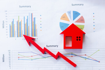 The red wooden house is placed on the graph or business information. Business growth concept. Economic chart. Real estate market. Mortgages. High profit home taxes for business investments.