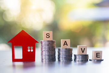 Savings. Investing in real estate. Graph of the growth of a pile of silver coins and a red wooden house. Loans to buy a home. Wooden letters blocks writing words notes Save for the future.
