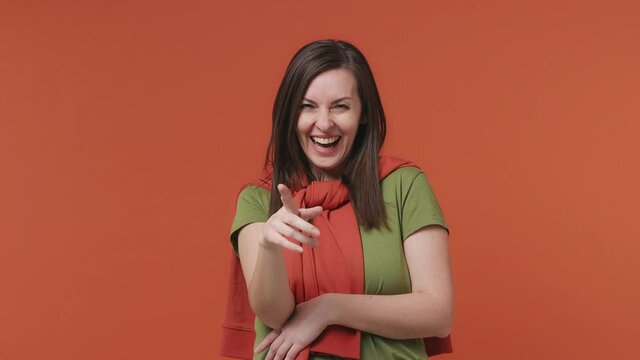 Excited fun young woman 30s years old wears basic casual olive green khaki t-shirt look camera laugh smiling watch comedy movie pointing index finger on you isolated on bright orange color background