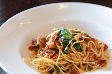 Spicy spaghetti with fried bacon. Spaghetti with fried crispy bacon and chili fried basil leave.