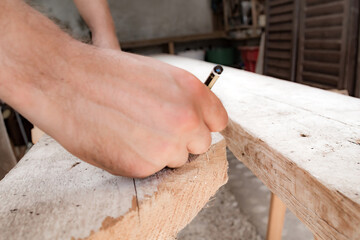 Male carpenter working with wood material in a garage.