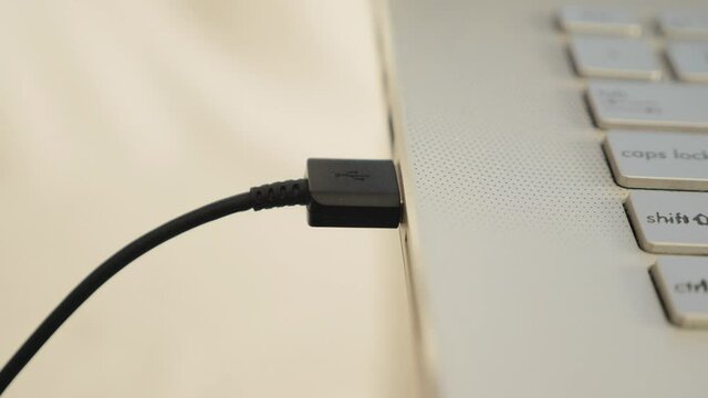 Close up of hand inserting plugging data cable into usb port in laptop, data transfer