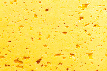 cut surface of a piece of milk natural cheese with holes background texture
