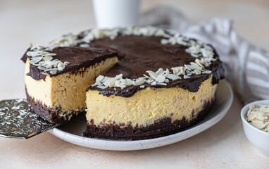 Delicious creamy cheesecake decorated with chocolate glaze and almond, light concrete background. No bake mousse dessert.