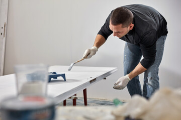 Young adult man painting on a DIY budget renovation of his new home apartment.