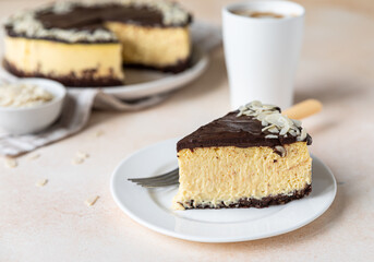 Slice of no baked creamy cheesecake with chocolate glaze and almond, light concrete background.