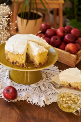 Sponge cake with apples garnished with whipped cream on a green plate on the table. Homemade pie