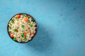 White rice with vegetables, top shot on a blue background