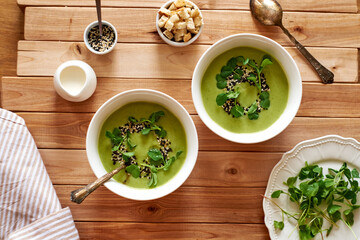 broccoli puree soup with sesame seeds, croutons and herbs. wooden background, top view
